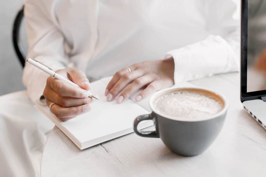 Woman writing in her journal enjoying coffee: best fall flavored coffee to try
