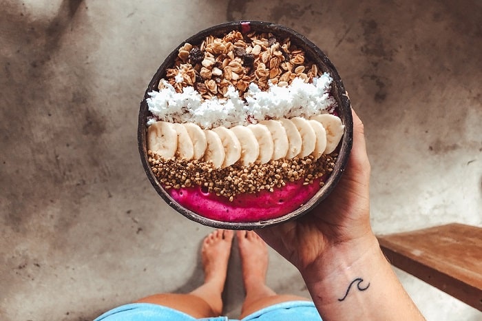 Smoothie bowl with fruit and granola in a wooden bowl