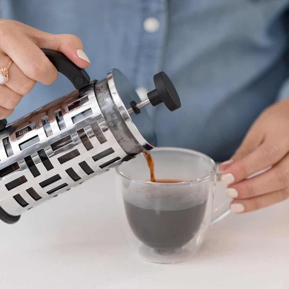 woman pouring steaming hot coffee into a mug